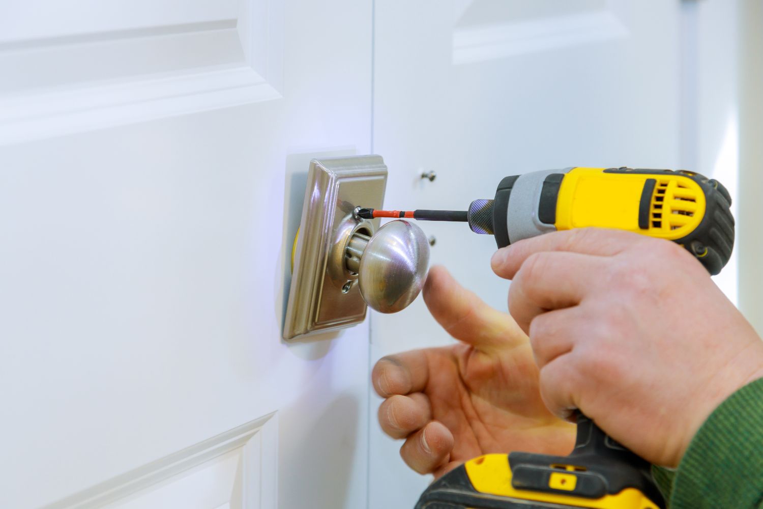 handyman-using-a-drill-to-installing-lock-in-door-2022-12-01-18-19-53-utc